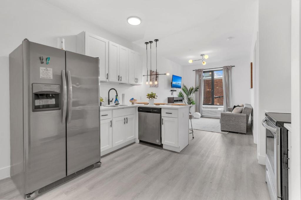 una cocina con electrodomésticos de acero inoxidable y armarios blancos en Luxe 1 BR apt EWR Prudential Center, en Elizabeth