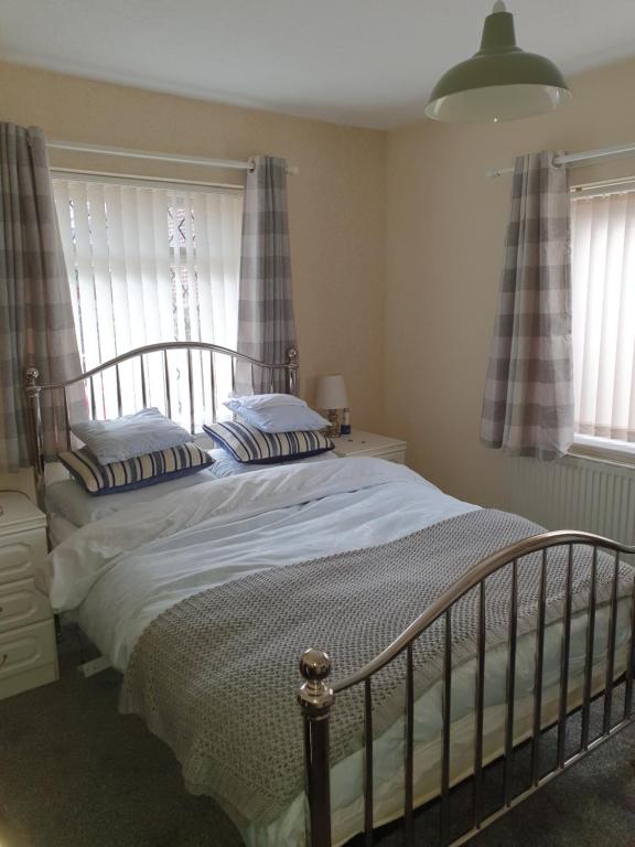 a bed in a bedroom with two windows at Ellesmere port in Sutton