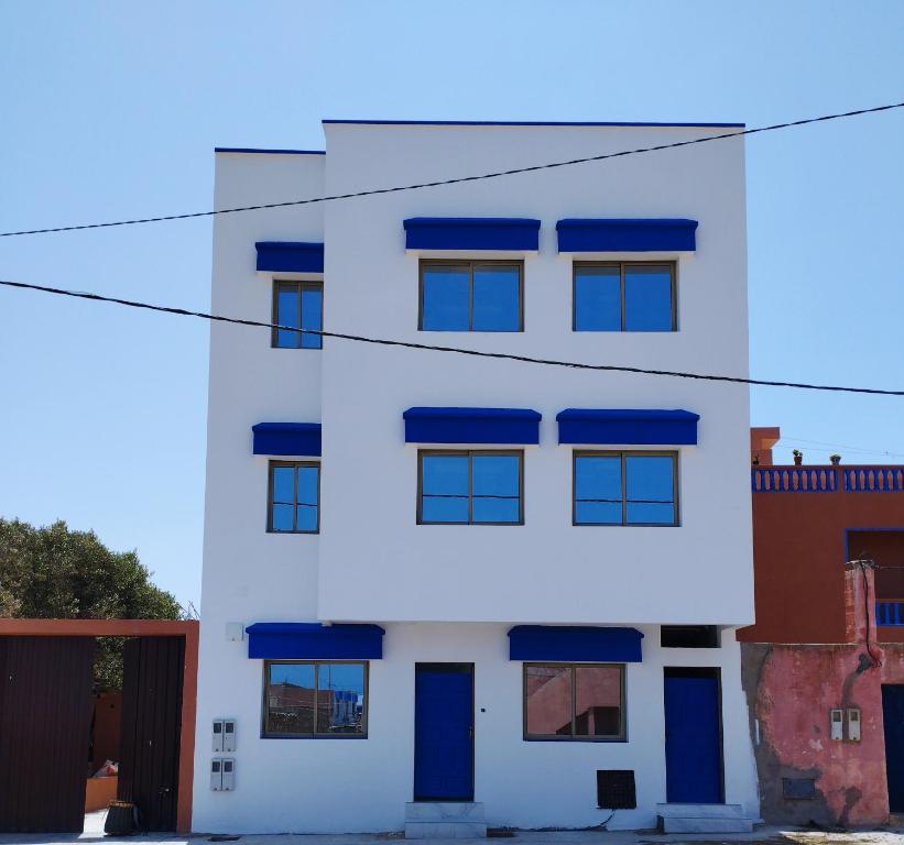 a white building with blue windows at Appartement Hajar in Oualidia