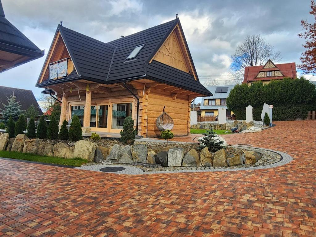 a house with a black roof on a brick driveway at LITTLE KOIS VILLAGE in Dzianisz