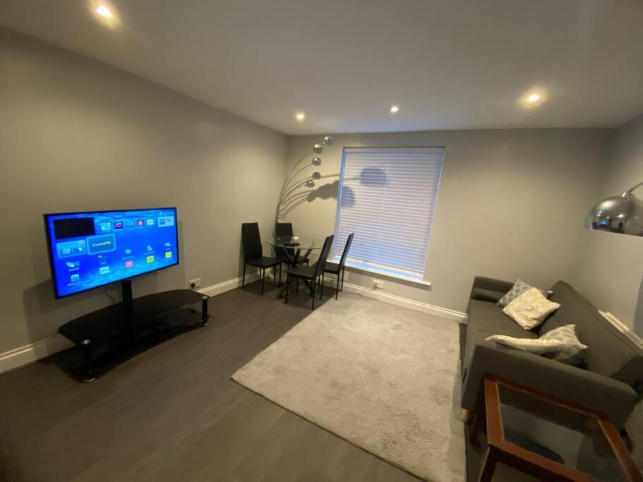 Spacious 2 bedroom flat london في لندن: غرفة معيشة بها أريكة وتلفزيون وطاولة