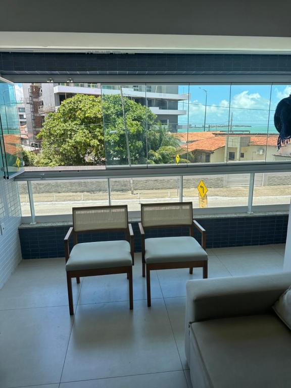 three chairs and a couch in a room with a window at Apartamento beira mar in João Pessoa