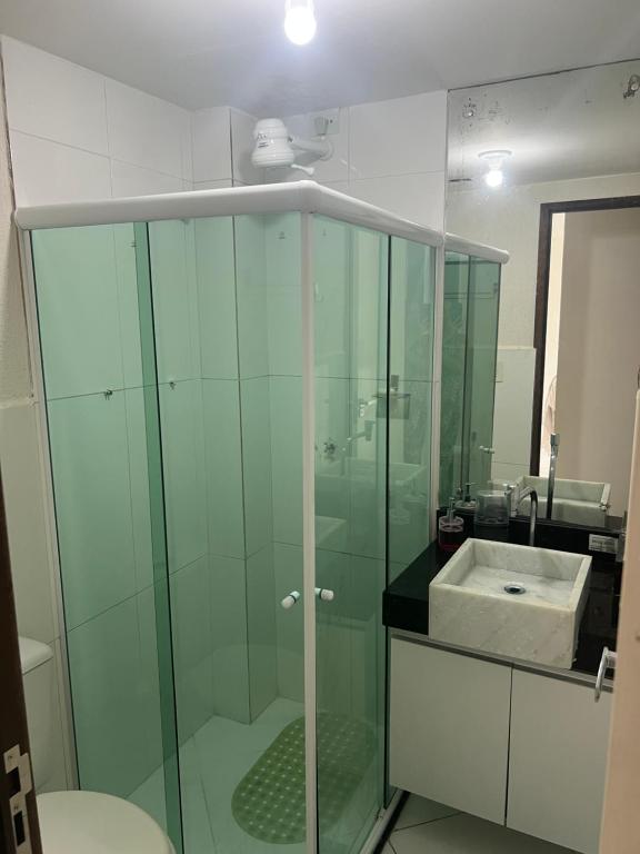 a bathroom with a glass shower and a sink at Mar e sol residencial 2 quartos com ar condicionado,500 metros da praia de Jacumã in Conde