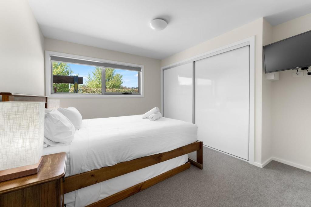 a bedroom with a large bed and a window at T Bar on Twynam - Modern 2BR Apartment l WiFi l Netflix l BBQ l Smart TV l Air-Con in Jindabyne