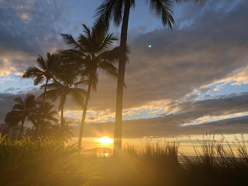 einen Sonnenuntergang mit Palmen am Strand in der Unterkunft Em fase de exclusão não reservar in Bertioga