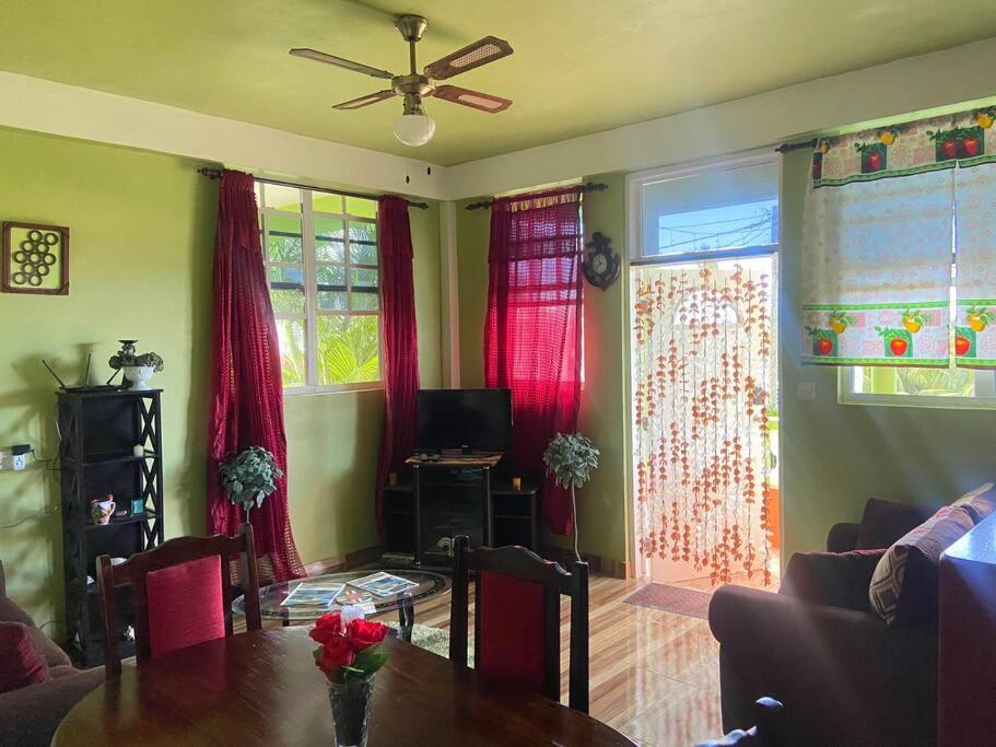 a living room with a table and red curtains at Dangleben’s Apartment in Pointe Michel