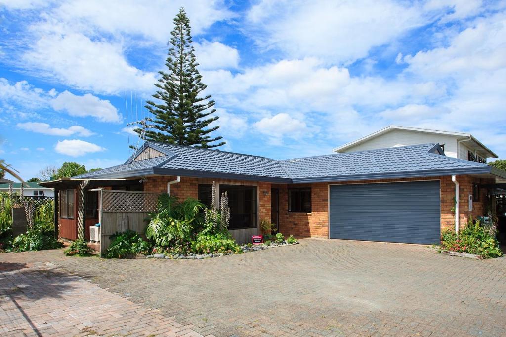a brick house with a garage and a tree at Denby Crest in Whangarei