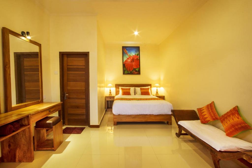 una camera con letto, divano e specchio di Tebesaya Homestay ad Ubud