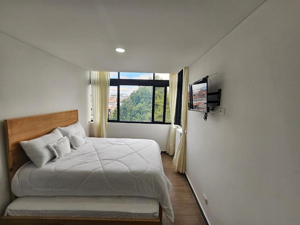 Schlafzimmer mit einem Bett, einem TV und einem Fenster in der Unterkunft Apartamento Meredi in Bogotá