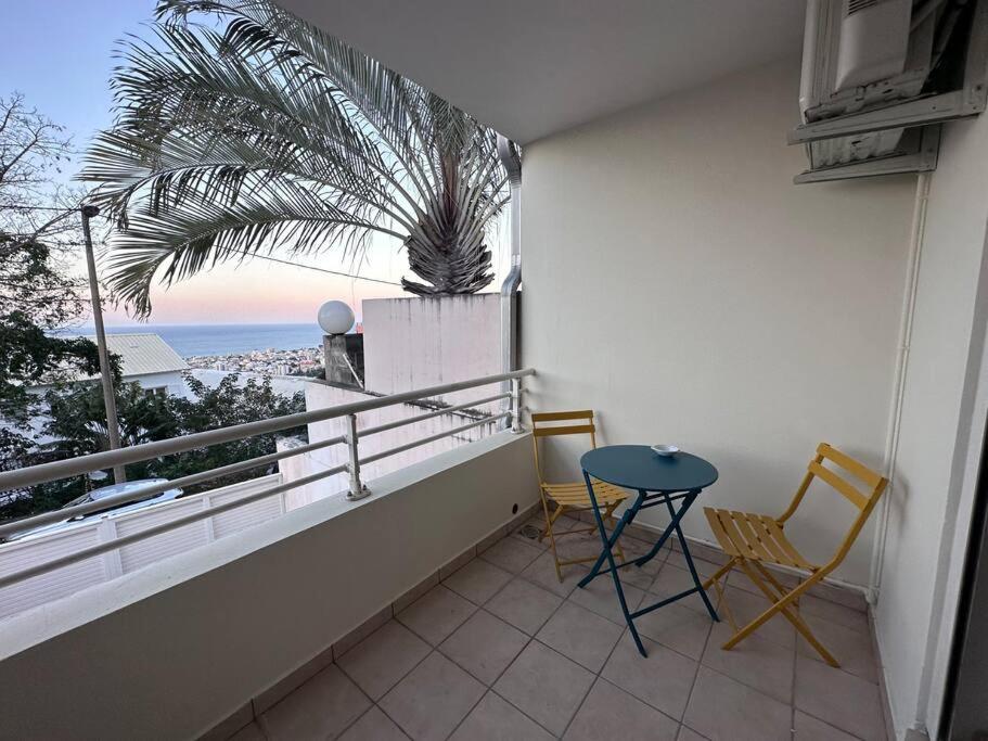 a balcony with a table and chairs and a view of the ocean at Studio Bellepierre, vue mer in Saint-Denis