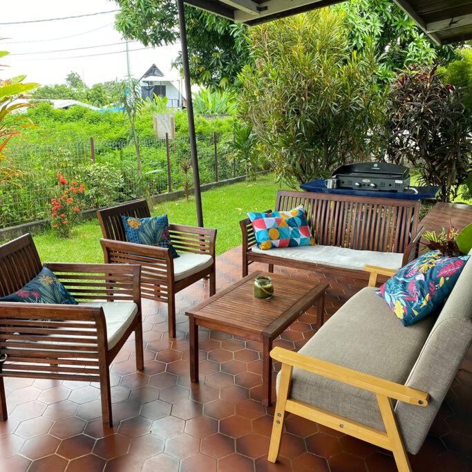 a patio with chairs and tables and a grill at Tahitian villa avec accès mer privé à 300 m in Punaauia