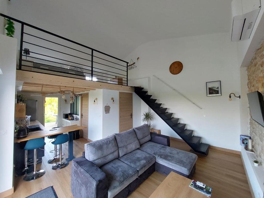 ein Wohnzimmer mit einer Couch und einer Treppe in der Unterkunft La Cabane de Nina, cottage chaleureux in Plassac