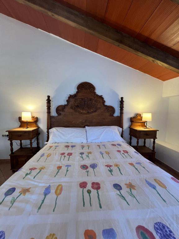 a bed in a bedroom with two lamps on two tables at Casa Rural “Los Campos” in Almogía