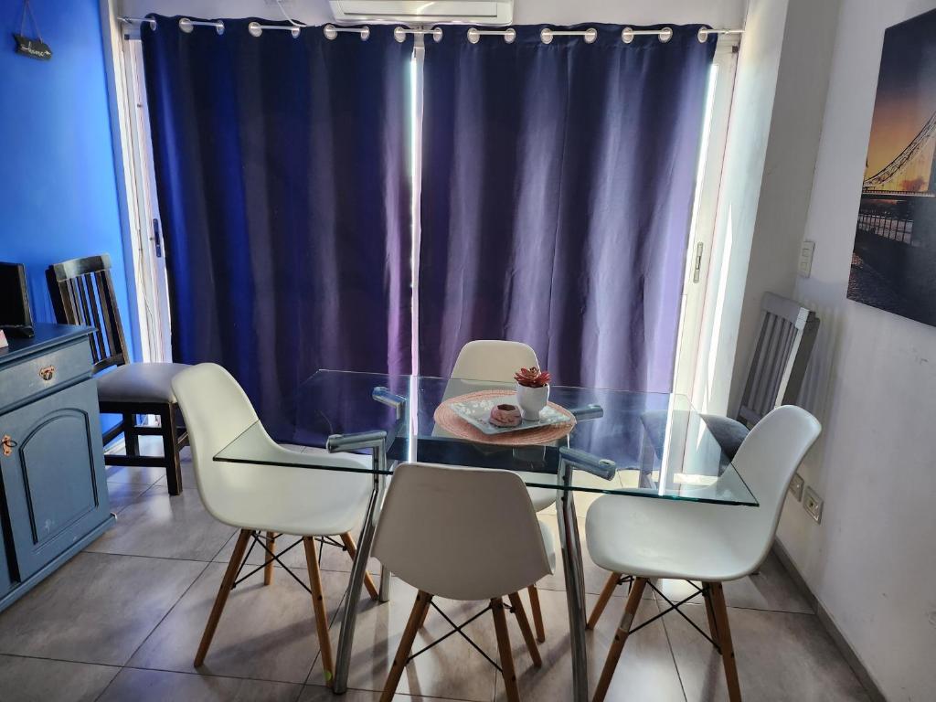 comedor con mesa de cristal y sillas blancas en Departamentos Dany en Buenos Aires