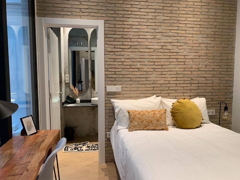a bedroom with a white bed and a brick wall at La Reina Beach rooms in Valencia