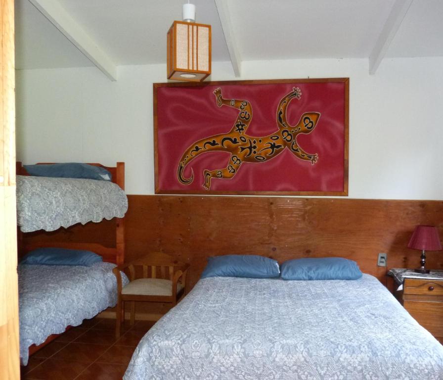 - une chambre avec un lit et une peinture murale dans l'établissement Cabaña Kaiheke, à Hanga Roa