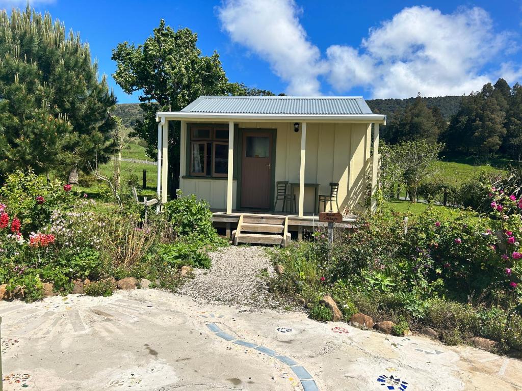 een klein huis met een veranda op het strand bij Wisteria Way in Opononi