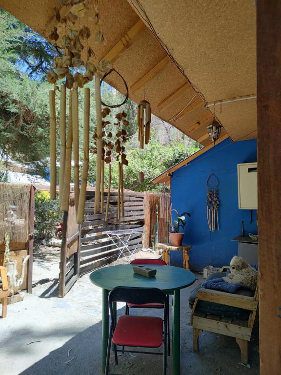 un patio con mesa, sillas y una pared azul en CABAÑA JACARANDA, en Horcón
