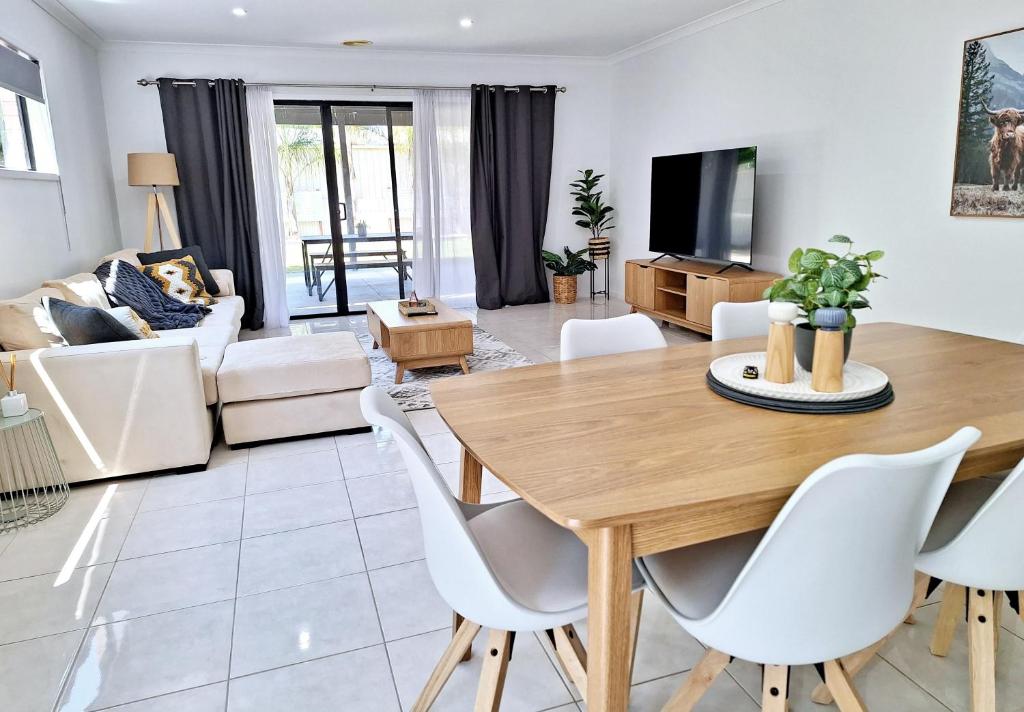 sala de estar con mesa de madera y sillas blancas en Townhouse on Greybox, en Kialla