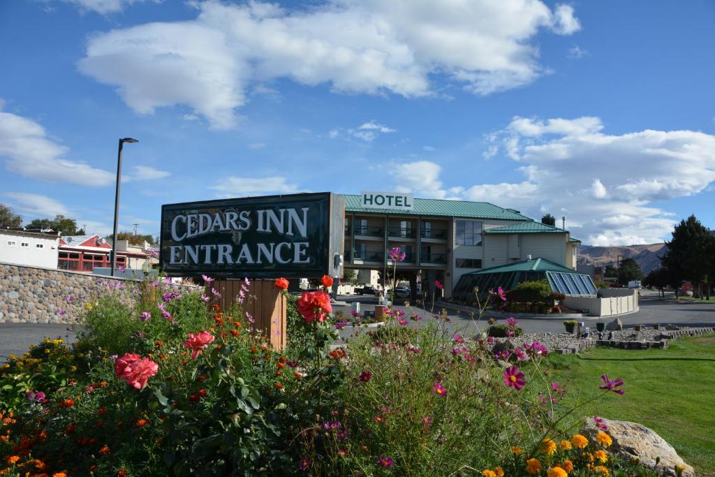 ein Schild vor einem Hotel mit Blumen in der Unterkunft Cedars Inn in Wenatchee