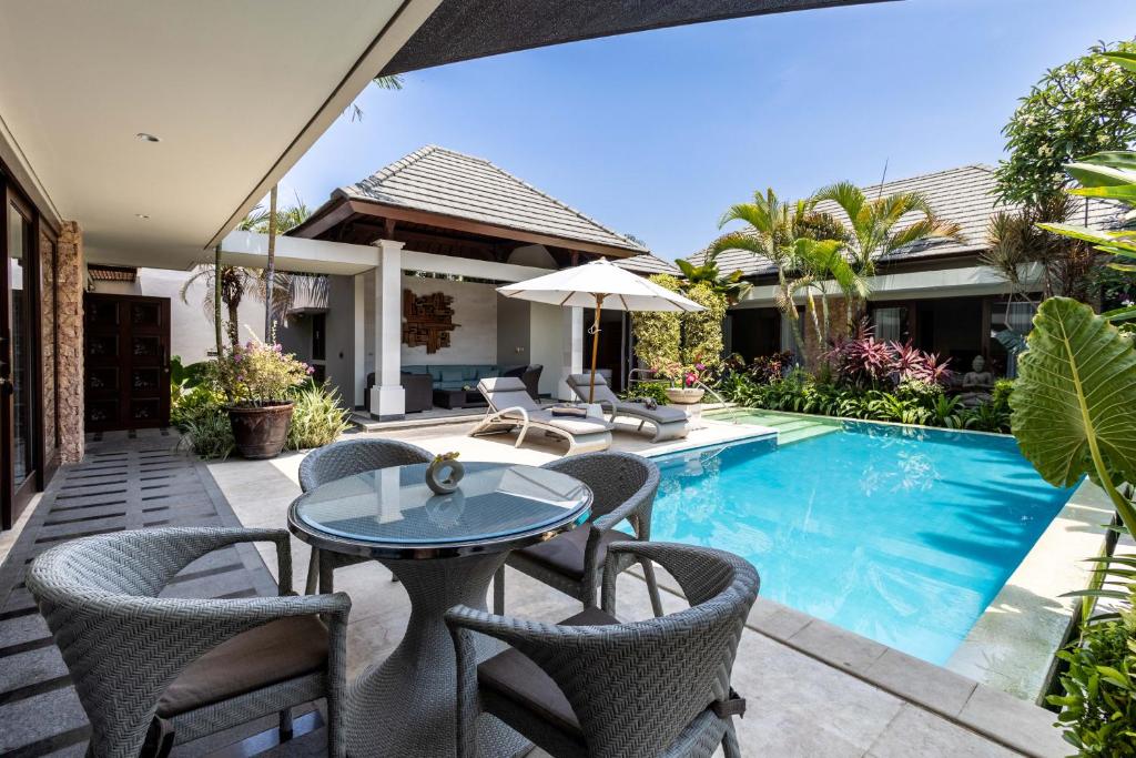 un patio con tavolo e sedie accanto alla piscina di Kejora Beachfront Estate Sanur - Luxurious Villa Seven Kejora a Sanur