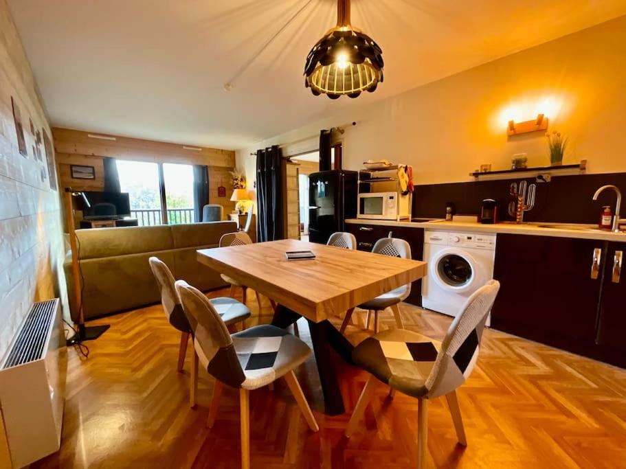 eine Küche und ein Esszimmer mit einem Holztisch und Stühlen in der Unterkunft Les Xettes, bel appartement style chalet avec vue in Gérardmer