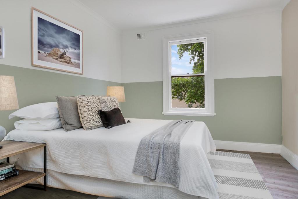 a white bedroom with a bed and a window at Native Rose Hotel in Sydney