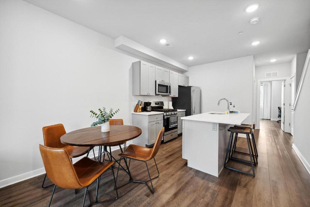 フィラデルフィアにあるLuxurious Condo with Rooftop and Parking near University Cityのテーブルと椅子のあるキッチンと白いキャビネットのあるキッチン