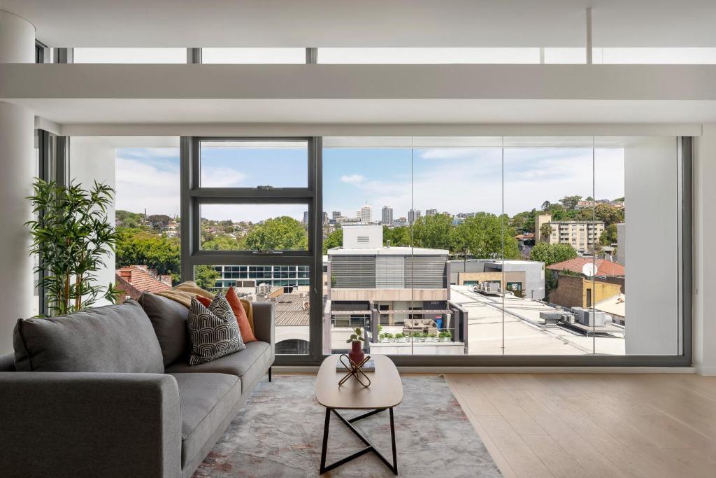 a living room with a couch and a large window at Urban Rest Double Bay Apartments in Sydney