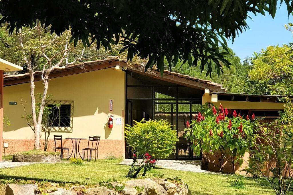 een huis met een tafel en stoelen in een tuin bij Ecolodge Guancascos, cabaña para 16 personas al pie del PN Celaque in Villa Verde