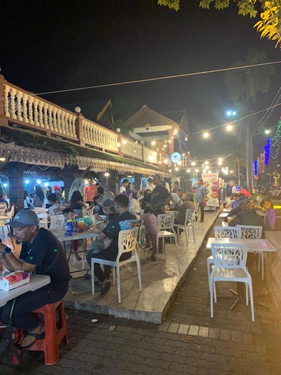 a group of people sitting at tables at a restaurant at night at Andiana Hotel & Lodge - Kota Bharu City Centre in Kota Bharu