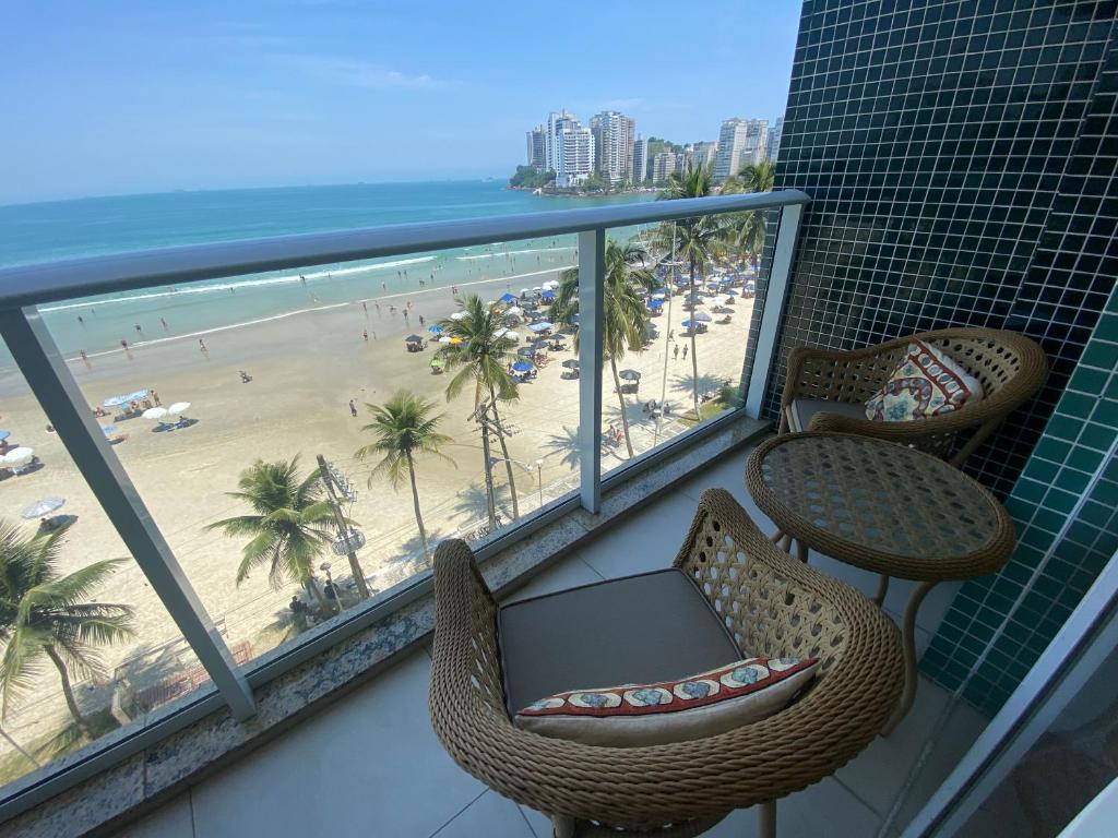 a balcony with chairs and a table and a beach at Guarujá Pé na Areia in Guarujá