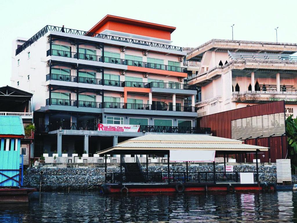 a boat in the water in front of a building at River Kwai View Hotel - SHA Extra Plus Certified in Kanchanaburi City