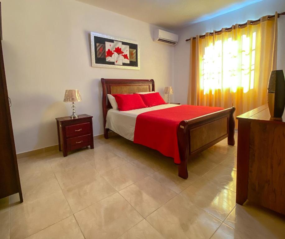 a bedroom with a bed with red pillows and a window at Perfecto para Descansar y Desconectarse Villa Zapata - Apartamentos Turísticos in San Cristóbal