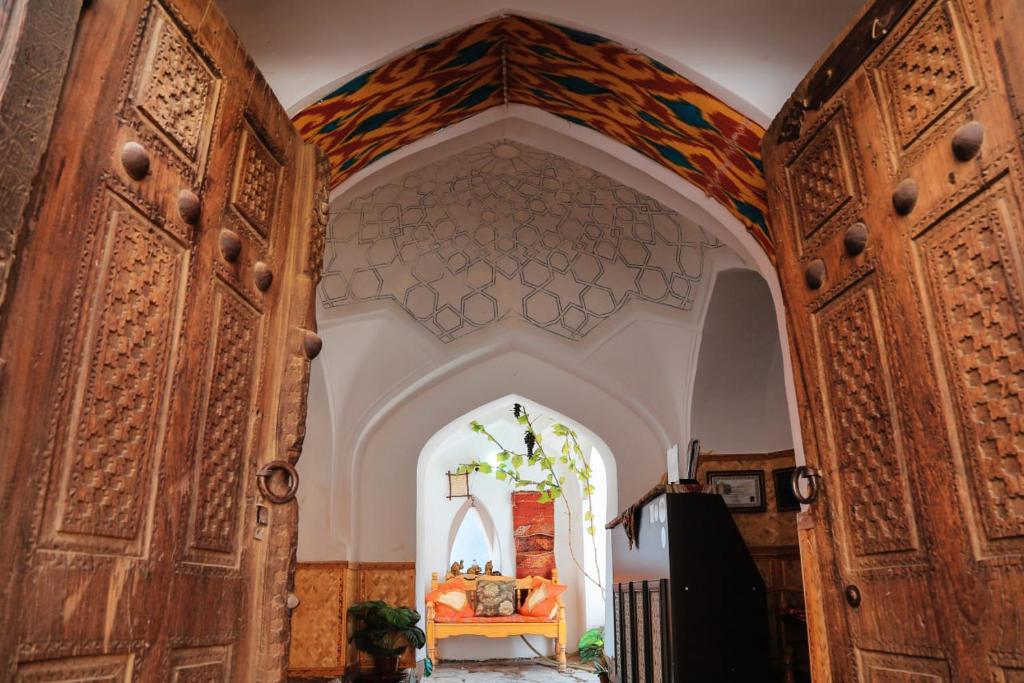 uma entrada para um quarto com um arco e portas de madeira em Karavansaray Xurjin Old em Bukhara