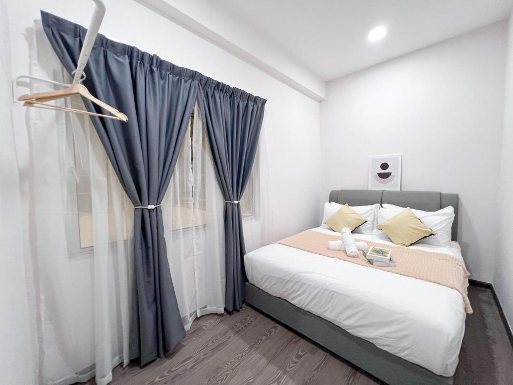 a bedroom with a bed with blue curtains and a window at Maison Signature Suites in Kuala Lumpur