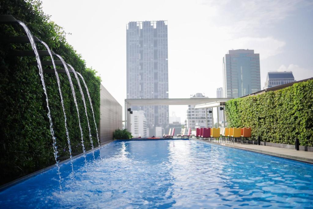 a swimming pool with a fountain in a city at ibis Styles Bangkok Silom in Bangkok