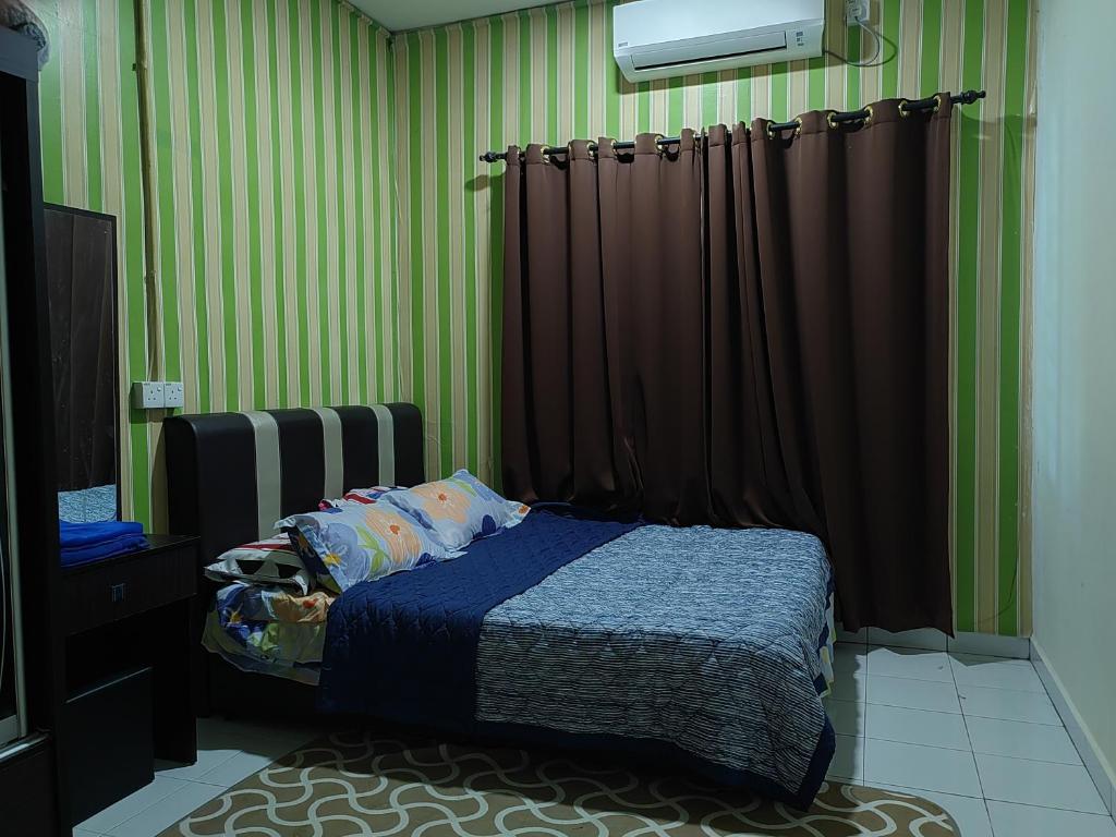 1 dormitorio con paredes de rayas verdes y 1 cama en Teratak Delisha -musslim en Kampong Jemampar