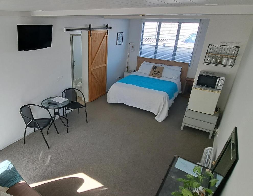 um quarto com uma cama, uma mesa e uma televisão em Guest Nest in Whitianga - 2 min walk to Beach em Whitianga