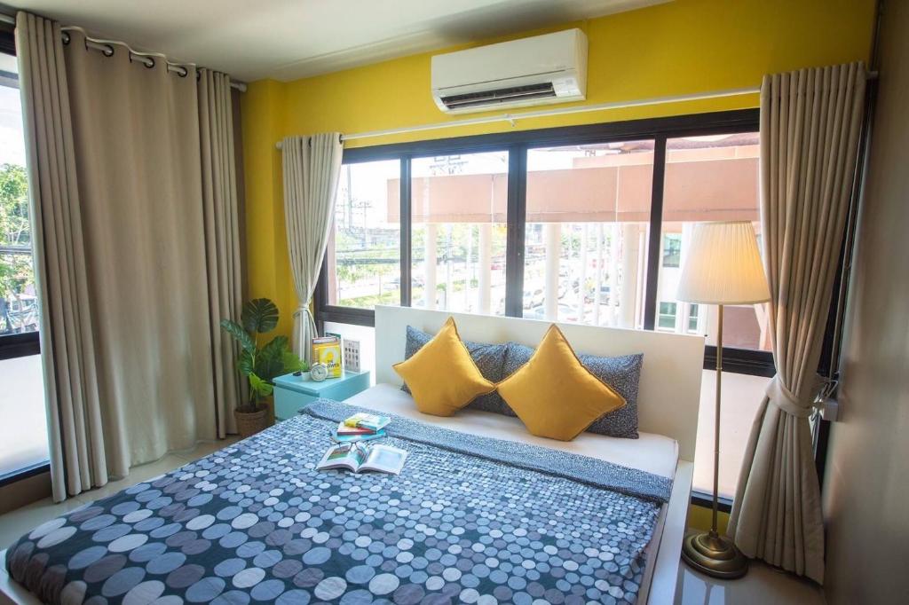 um quarto com uma cama com paredes amarelas e uma janela em Peony's Home em Ban Don Muang (1)
