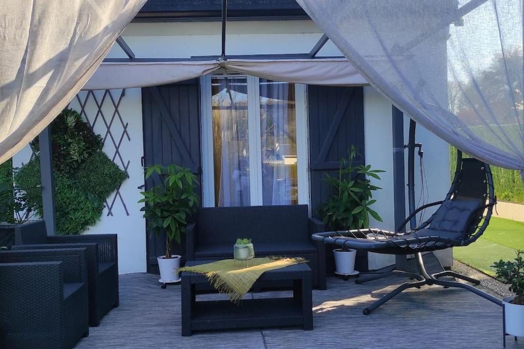 une terrasse avec un canapé, une chaise et une table dans l'établissement Jolie petite maison au calme, à Fourges