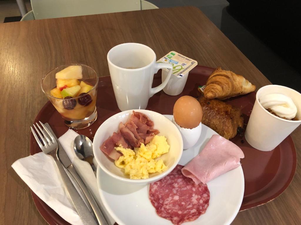 a breakfast tray with breakfast foods on a table at KYRIAD HONFLEUR - La Riviere Saint Sauveur in Honfleur