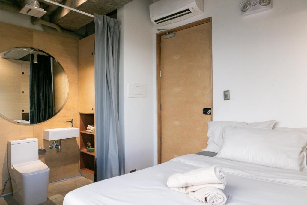 馬尼拉的住宿－HomeBase Kapitolyo - Minimalist Serviced Apartments，卧室配有白色的床和镜子