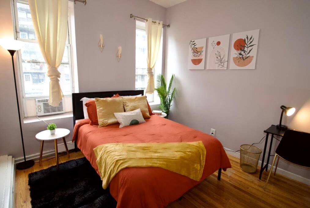 een slaapkamer met een bed met oranje lakens en een raam bij Tuk Ahoy - Cozy Condo Apartment in Brooklyn