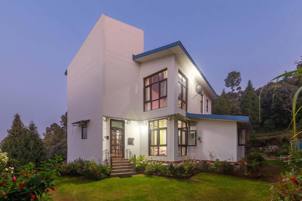 a white house with a lot of windows at Morning Bliss wih Bonfire at Ranikhet by StayVista in Rānīkhet