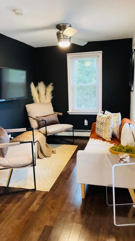 uma sala de estar com um sofá branco e uma parede preta em Cargo7 Cozy suites2 em North Providence