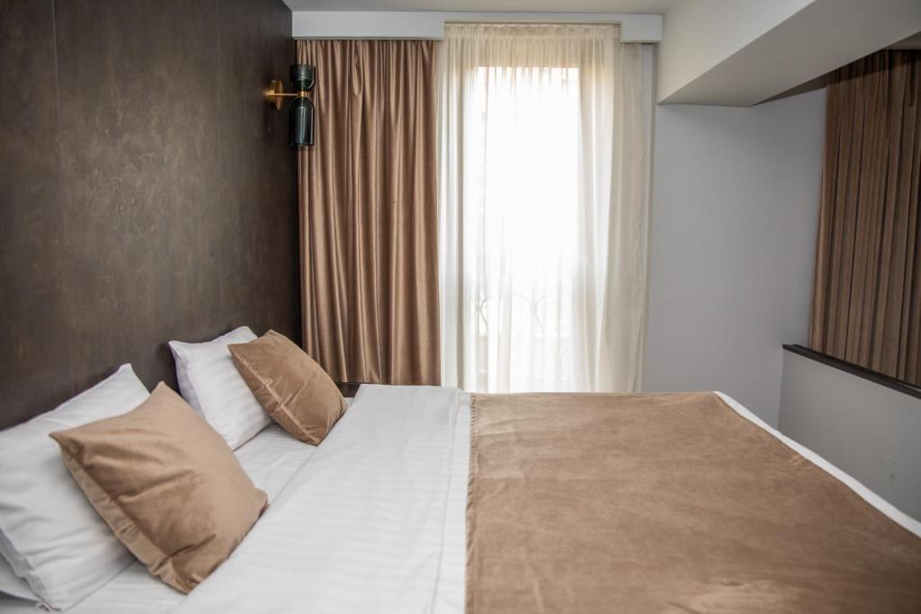 Un dormitorio con una cama blanca con almohadas y una ventana en Cascade Hotel en Ereván