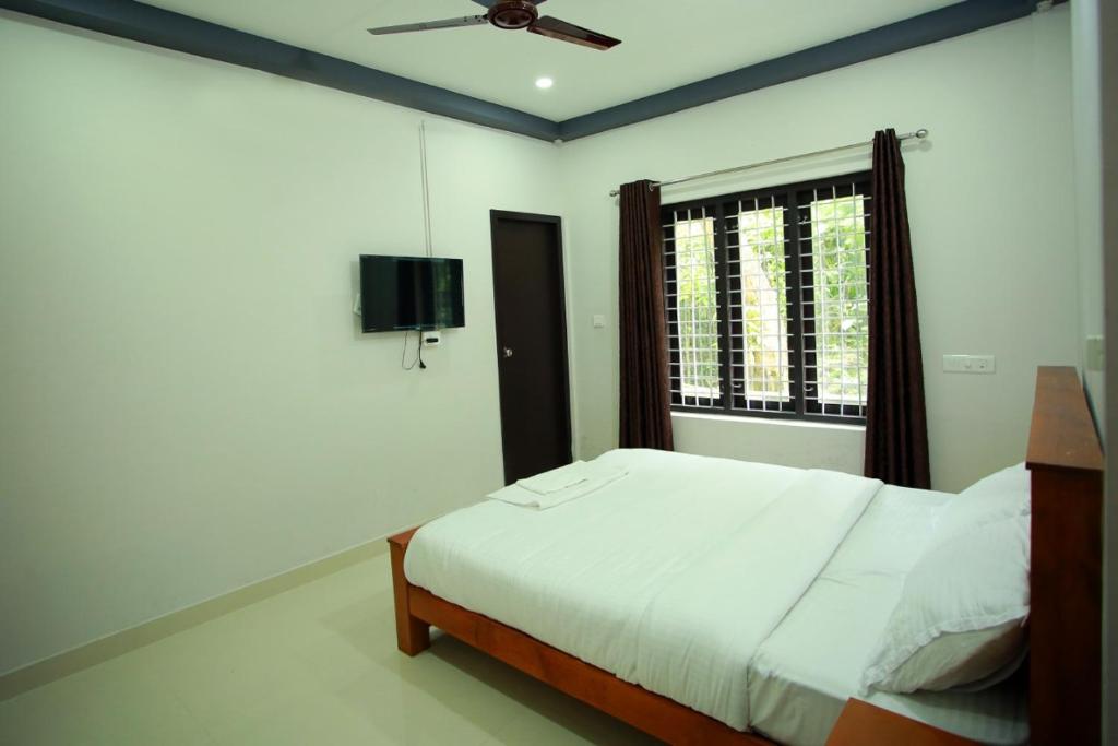 a bedroom with a bed and a window at Kosher Livings in Kalpetta