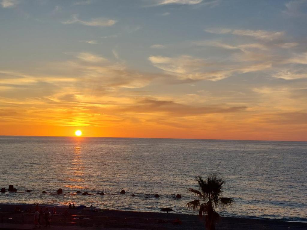 una puesta de sol en la playa con gente en el agua en Apartments Miro' en Capo dʼOrlando