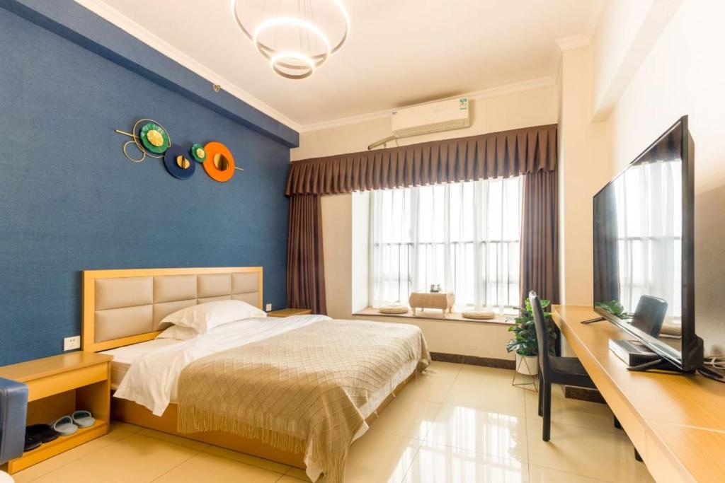 sypialnia z łóżkiem i telewizorem z płaskim ekranem w obiekcie 广州朴宿漫享公寓(琶洲国际会展中心店） w Guangzhou